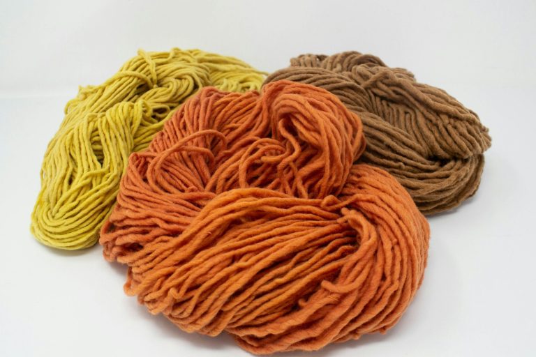 Alpaka oder Merino – Welche Wolle passt besser zu Ihnen? Drei Knäuel Merino Garn in den Farben Gelb, Orange und Braun.